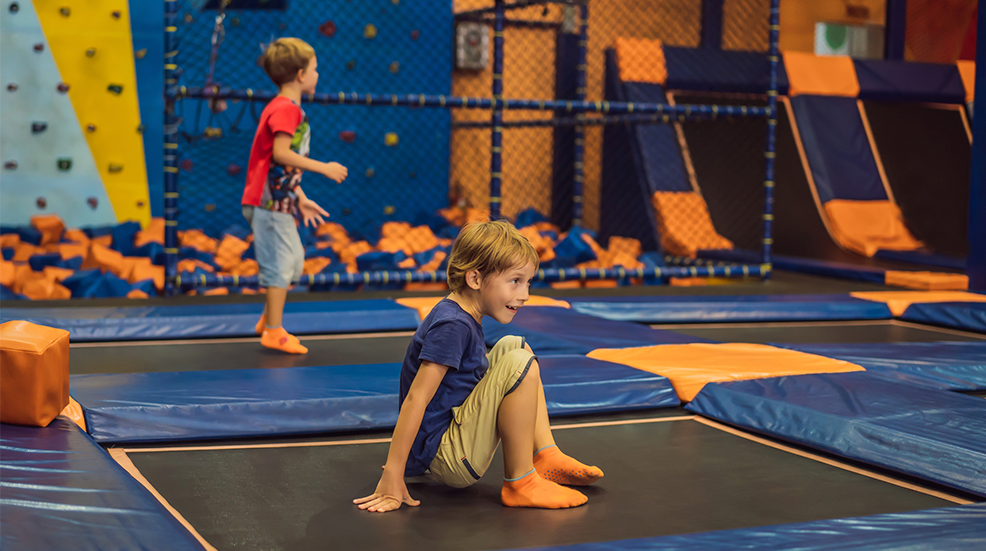 Cute boy jumping on trampoline in entertainment center.